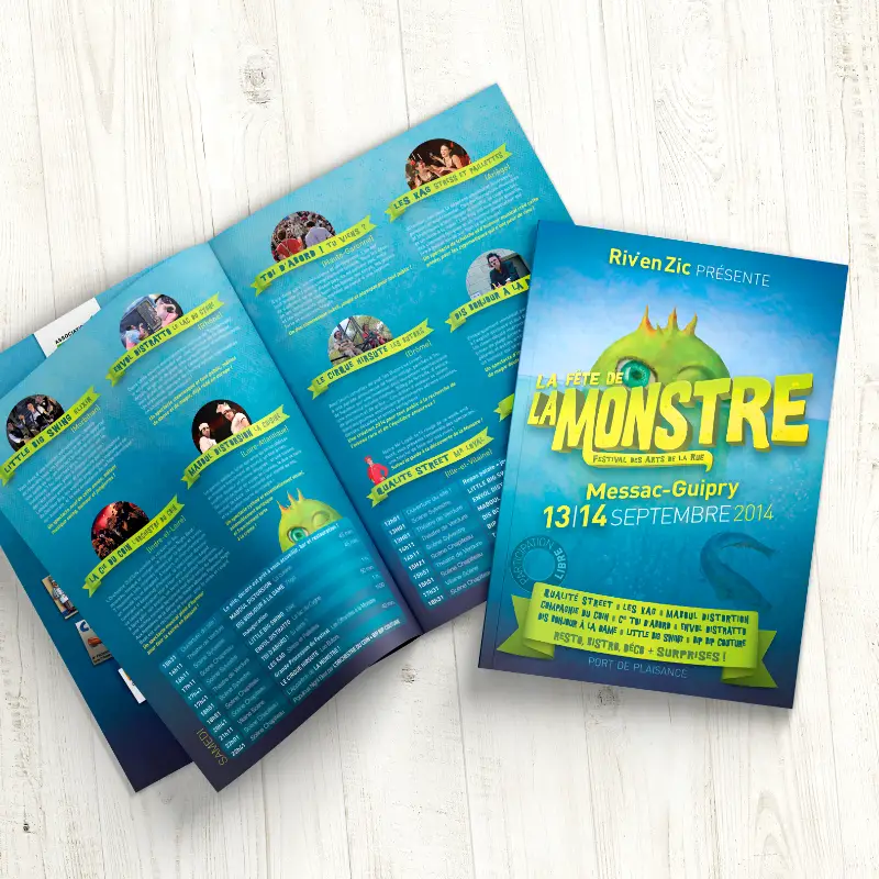 Couverture et pages int&eacute;rieures d&eacute;pli&eacute;es du programme bleu du festival La Monstre sur fond en bois clair